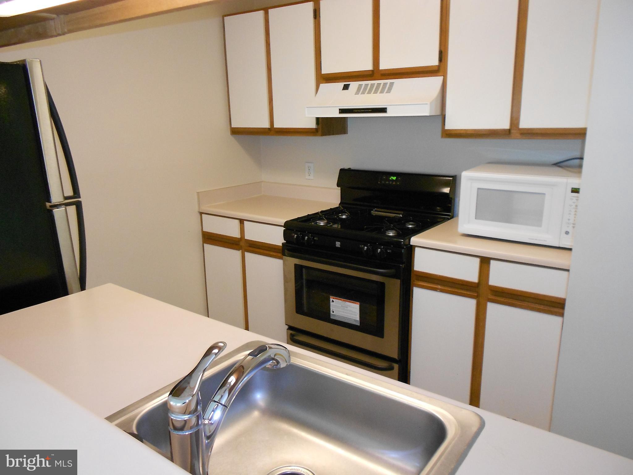 20950 Timber Ridge Terrace, Unit 203 Ashburn, VA 20147 - Photo 8 of 30 a kitchen with stainless steel appliances a stove a microwave and a refrigerator
