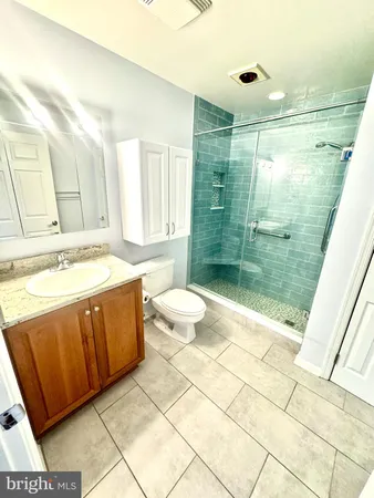 a bathroom with a granite countertop sink a toilet a mirror and shower