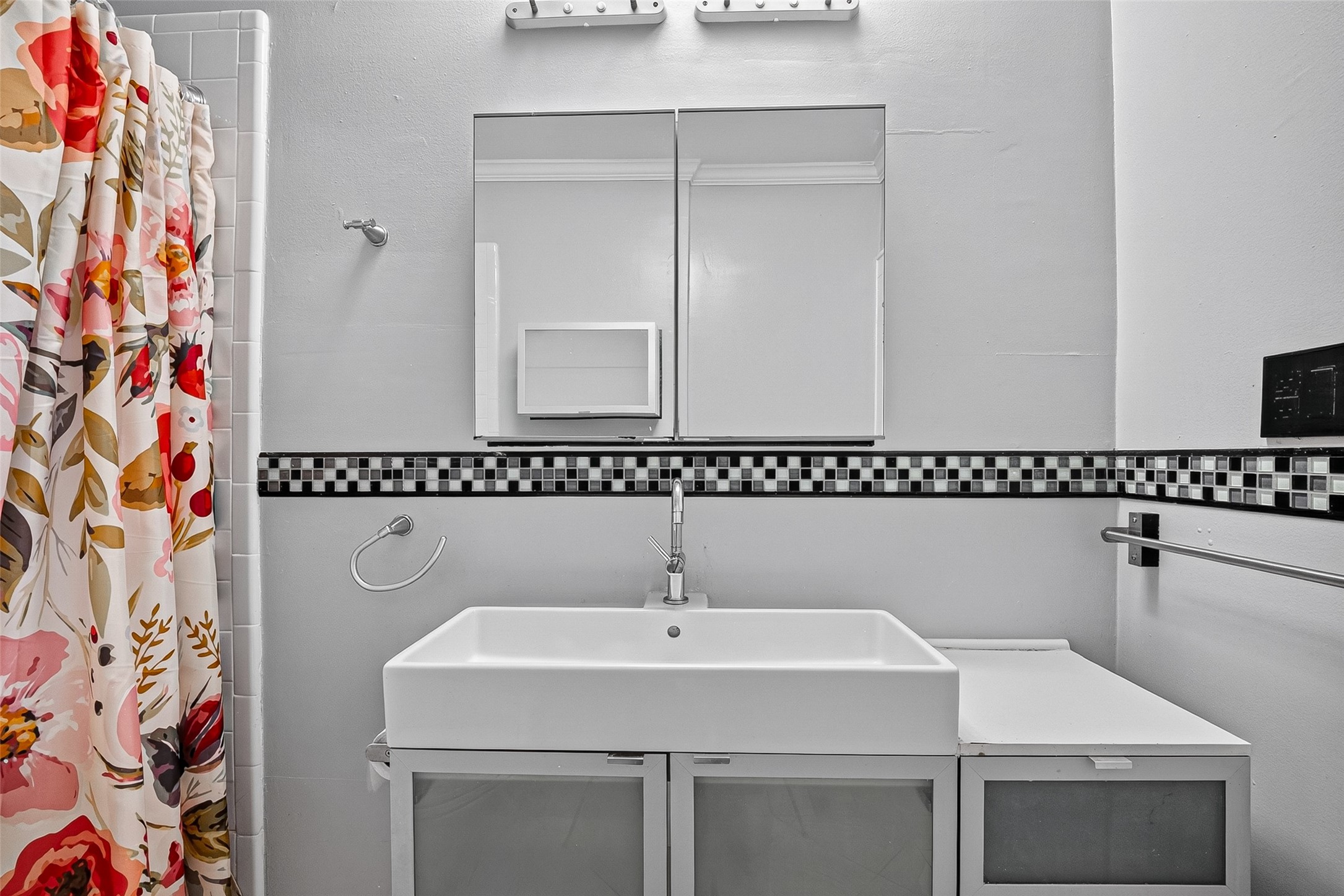 1758 Hawthorne Street, Unit 2 Houston, TX 77098 - Photo 14 of 19 This bathroom features a modern design with a sink atop a granite countertop. The space is accented with mosaic tiles and well-lit by contemporary fixtures, creating a stylish and functional setting.