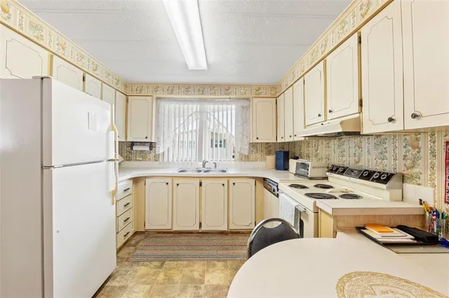 a kitchen with a refrigerator a stove a sink dishwasher and white cabinets with wooden floor