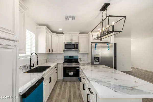 a kitchen with kitchen island granite countertop a sink appliances cabinets and counter space
