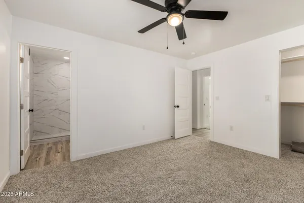 an empty room with closet and a chandelier fan