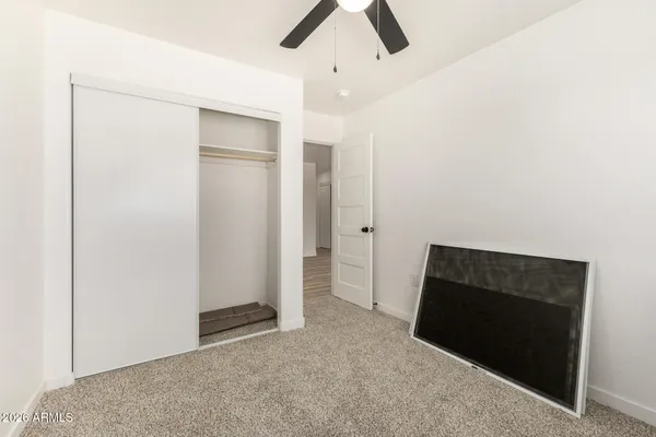 an empty room with closet and a ceiling fan