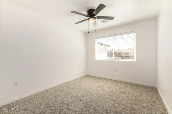 an empty room with a window and a ceiling fan