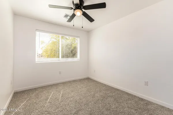 an empty room with a window and a fan