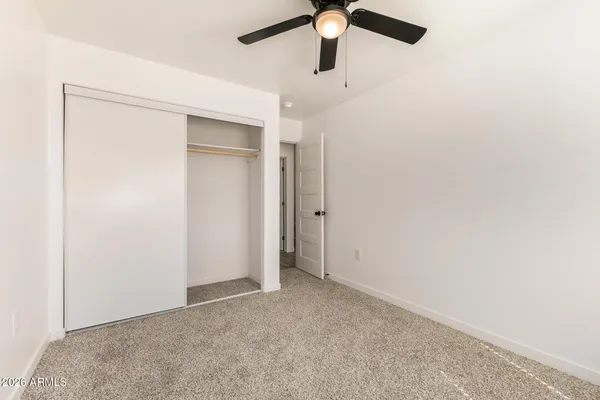 an empty room with a ceiling fan and a window