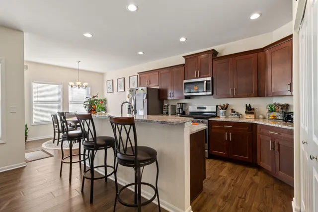 a kitchen with granite countertop a table chairs microwave and cabinets
