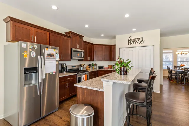 a kitchen with a refrigerator a stove a sink a dining table and chairs with wooden floor