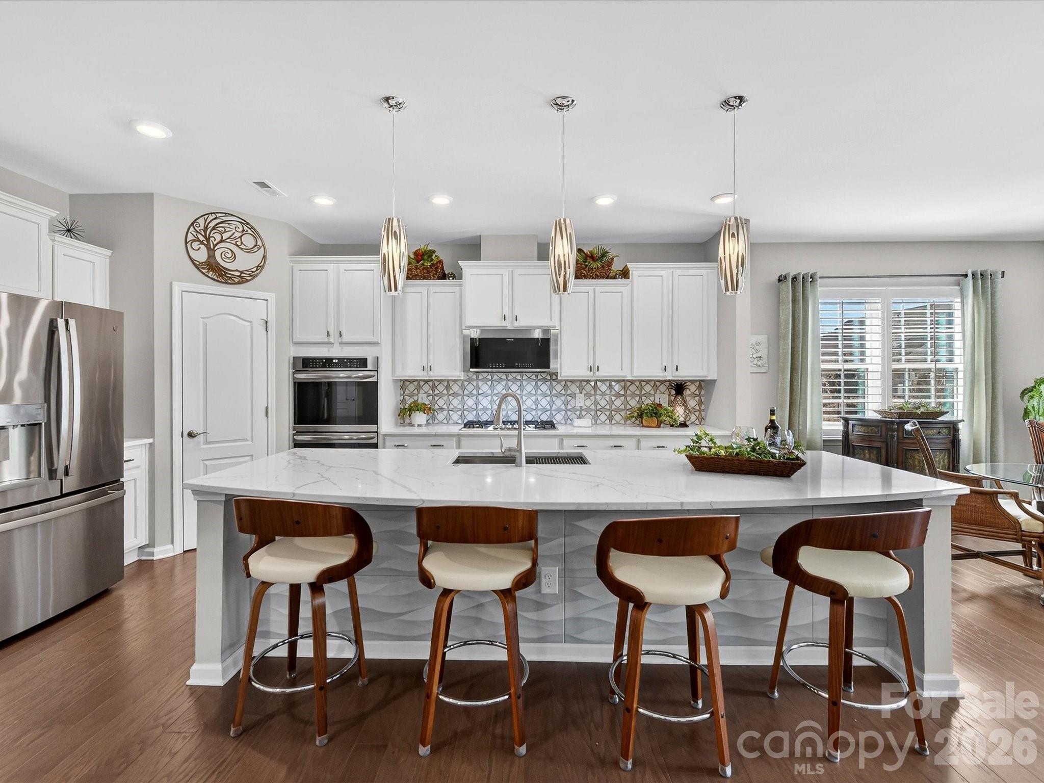 3355 Oliver Stanley Trail Lancaster, SC 29720 - Photo 14 of 48 a kitchen with stainless steel appliances kitchen island granite countertop a table chairs refrigerator and microwave
