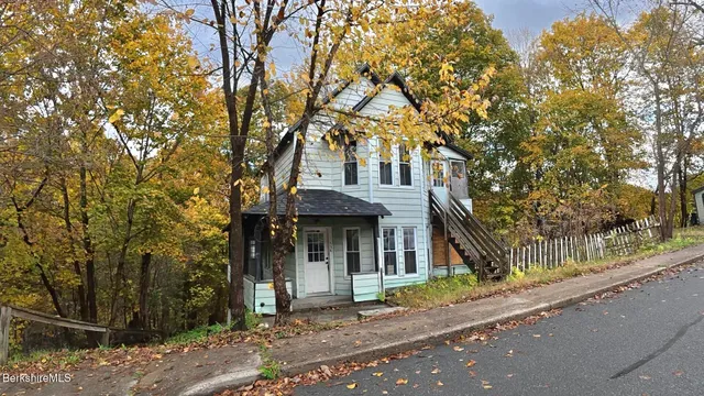 a view of a brick house next to a yard with large tree