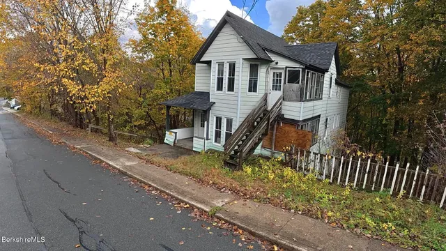a view of a house with a small yard and wooden fence