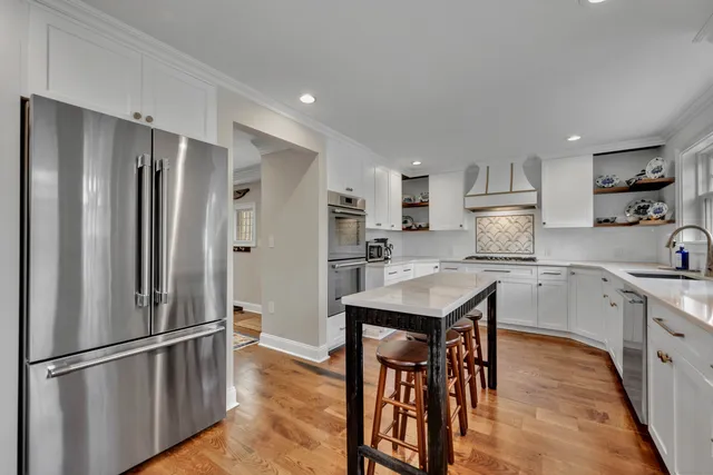 a kitchen with stainless steel appliances granite countertop a refrigerator a stove a sink dishwasher and a refrigerator with wooden floor