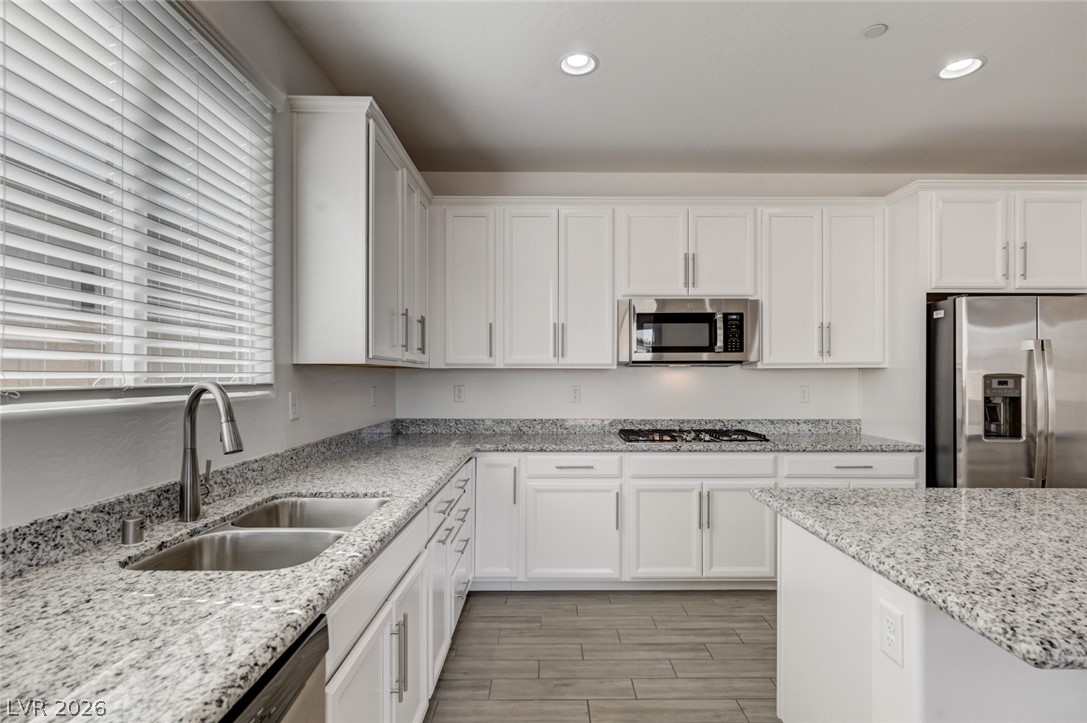 756 Cadence View Way Henderson, NV 89011 - Photo 9 of 45 Kitchen featuring white cabinets, stainless steel appliances, light stone countertops, wood tiled floors, and recessed lighting