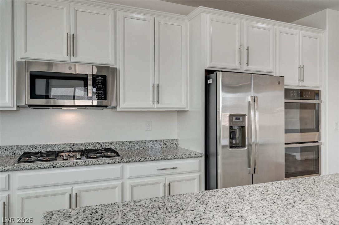 756 Cadence View Way Henderson, NV 89011 - Photo 10 of 45 Kitchen featuring stainless steel appliances, white cabinets, and light stone counters