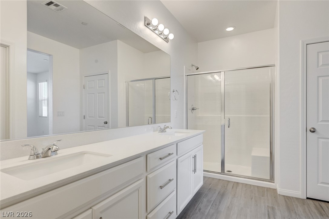 756 Cadence View Way Henderson, NV 89011 - Photo 16 of 45 Full bathroom featuring double vanity, a shower stall, and light wood finished floors