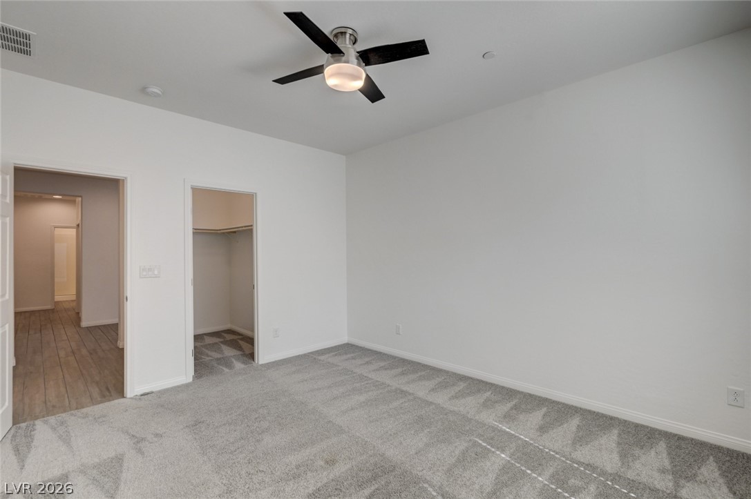 756 Cadence View Way Henderson, NV 89011 - Photo 24 of 45 Unfurnished bedroom featuring a spacious closet, light colored carpet, and a ceiling fan