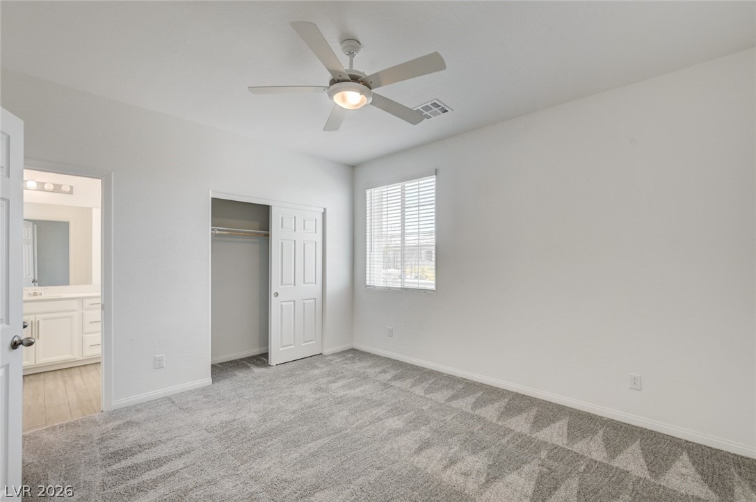 756 Cadence View Way Henderson, NV 89011 - Photo 28 of 45 Unfurnished bedroom with light colored carpet, ceiling fan, a closet, and connected bathroom