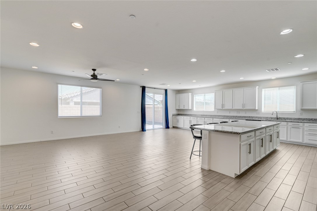 756 Cadence View Way Henderson, NV 89011 - Photo 43 of 45 Kitchen with white cabinets, a center island, a kitchen breakfast bar, light stone counters, and open floor plan