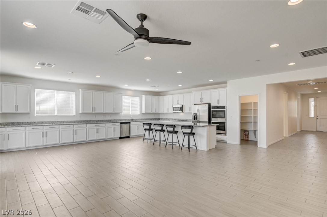 756 Cadence View Way Henderson, NV 89011 - Photo 5 of 45 Kitchen featuring white cabinets, a breakfast bar area, a kitchen island, stainless steel appliances, and recessed lighting