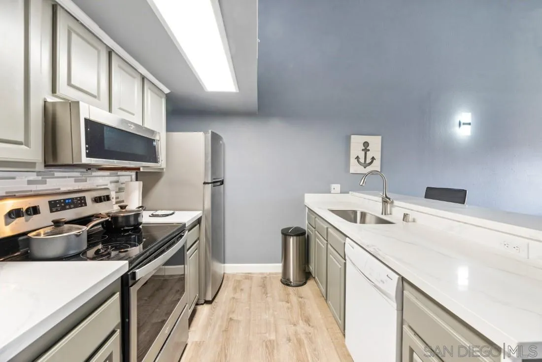 6131 Rancho Mission Road, Unit 323 San Diego, CA 92108 - Photo 2 of 11 a kitchen with a sink a stove top oven a refrigerator and a stove