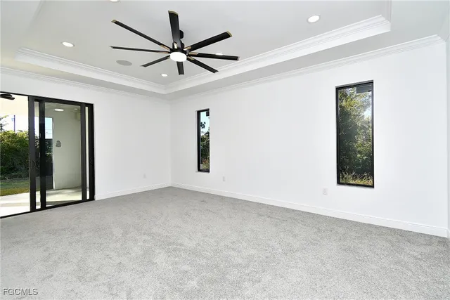 an empty room with ceiling fan and windows