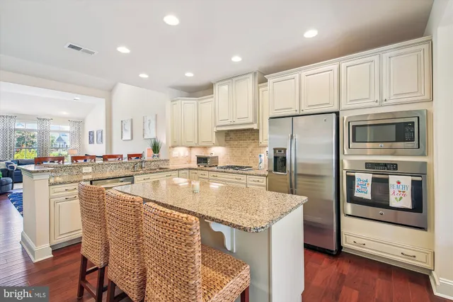 a kitchen with stainless steel appliances granite countertop a sink a stove a refrigerator cabinets and a counter top space