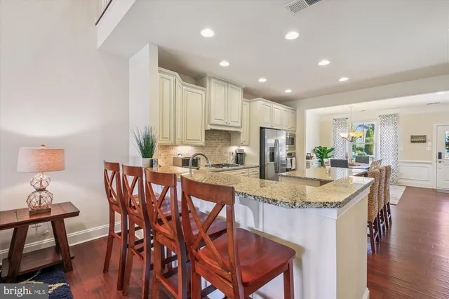 a kitchen with stainless steel appliances granite countertop a refrigerator a oven and white cabinets