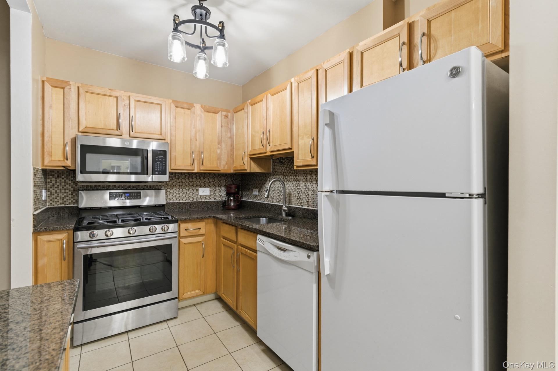 3044 3rd Avenue, Unit 9C Bronx, NY 10451 - Photo 12 of 15 Kitchen with appliances with stainless steel finishes, light tile patterned flooring, tasteful backsplash, and light brown cabinets