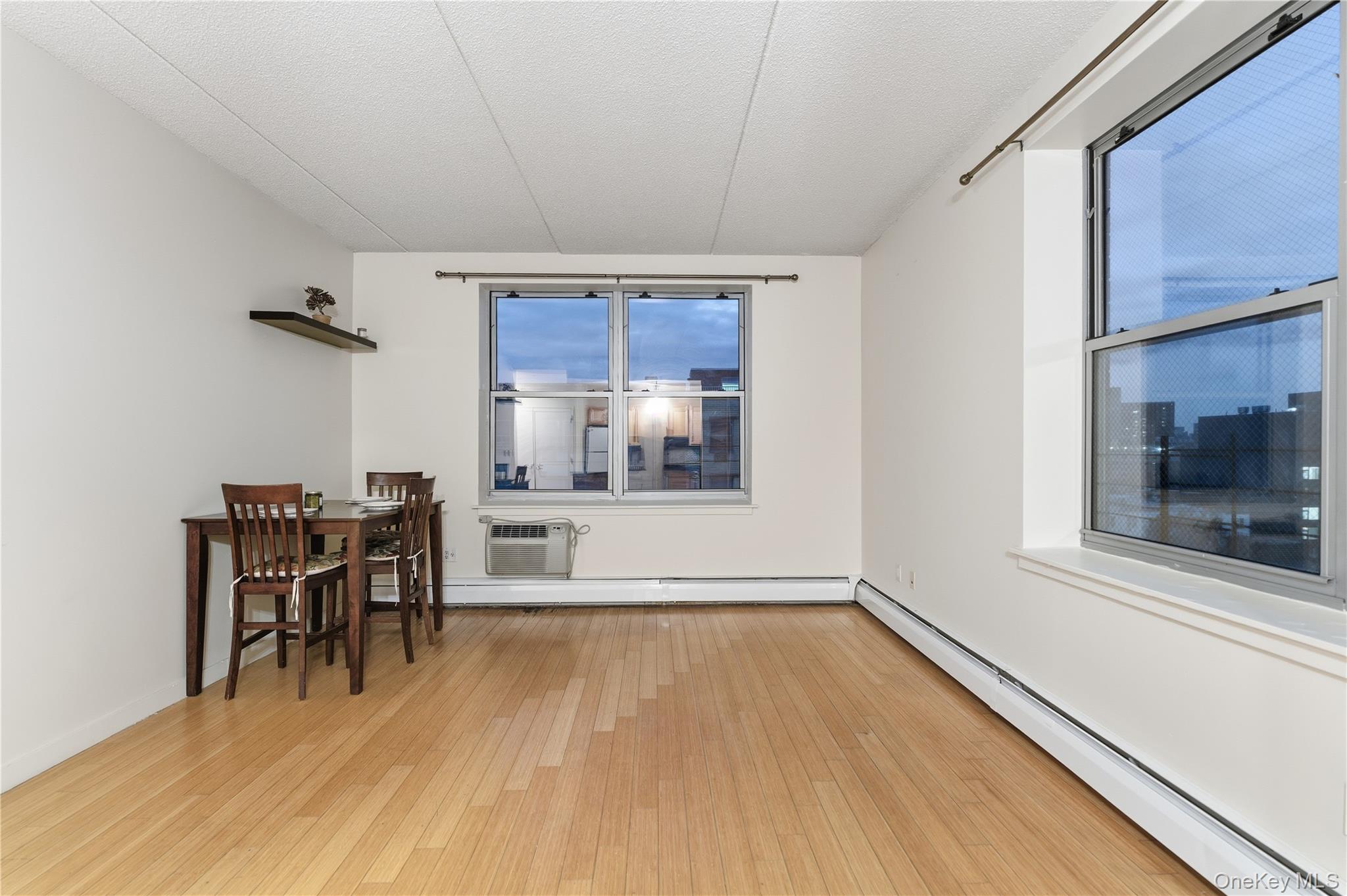 3044 3rd Avenue, Unit 9C Bronx, NY 10451 - Photo 15 of 15 Dining area with a baseboard heating unit, light wood finished floors, an AC wall unit, a textured ceiling, and a baseboard radiator