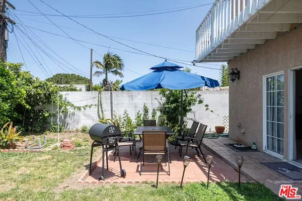 a view of patio with chairs and table under an umbrella