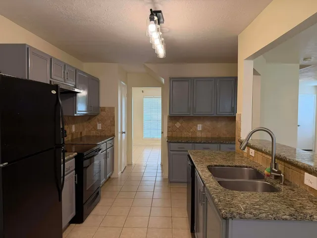 a kitchen with granite countertop a refrigerator and a sink