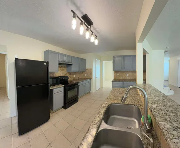 a kitchen with stainless steel appliances granite countertop a refrigerator a stove and a sink
