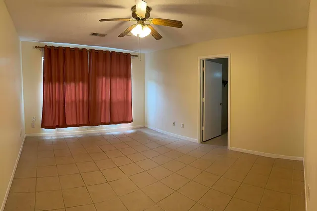 an empty room with a ceiling fan and a window