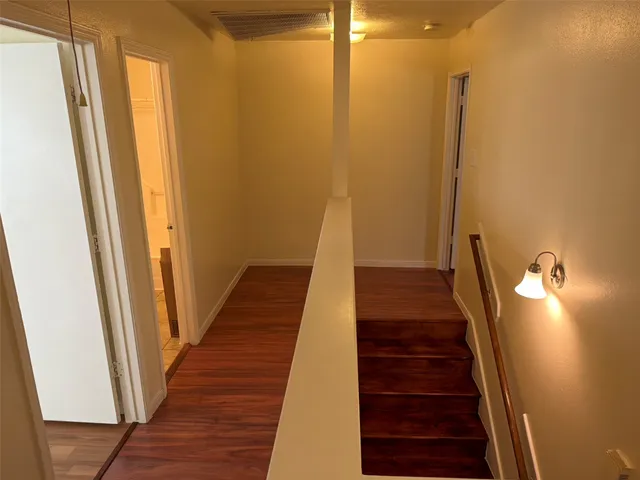 a view of a hallway with wooden floor and stairs