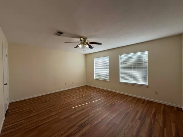 a view of an empty room with a window and wooden floor