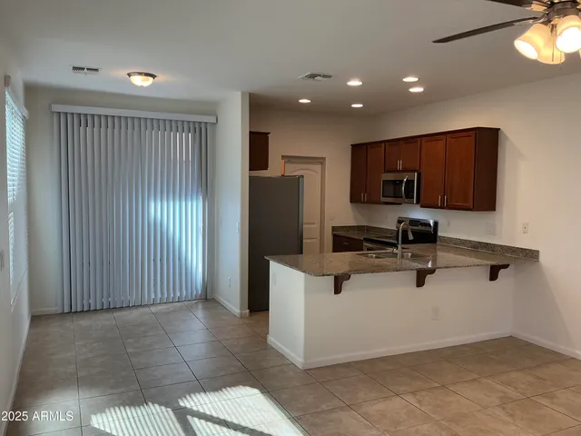 a view of kitchen with stainless steel appliances granite countertop refrigerator stove top oven and cabinets