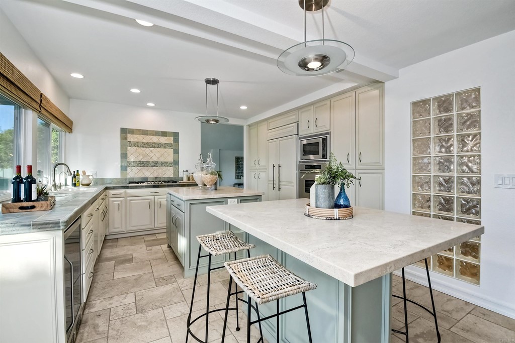 735 Santa Paula Solana Beach, CA 92075 - Photo 36 of 61 a kitchen with stainless steel appliances granite countertop a stove a sink a refrigerator cabinets and a dining table with chairs