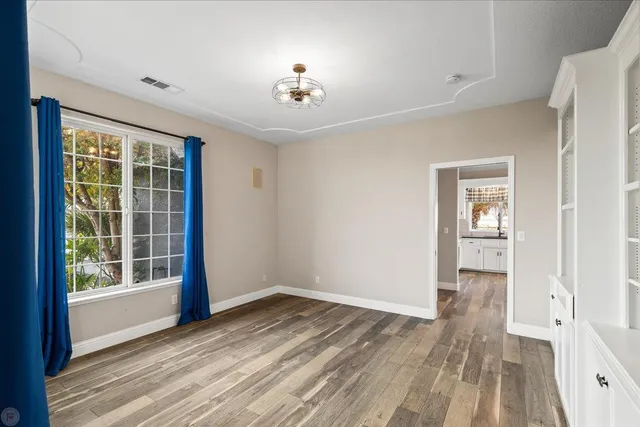 an empty room with a chandelier fan and windows