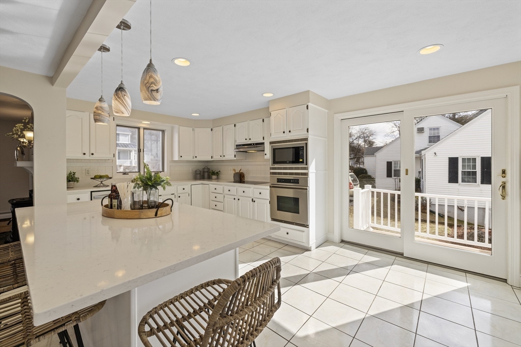 a kitchen with stainless steel appliances kitchen island granite countertop a refrigerator a stove a sink dishwasher and white cabinets with wooden floor
