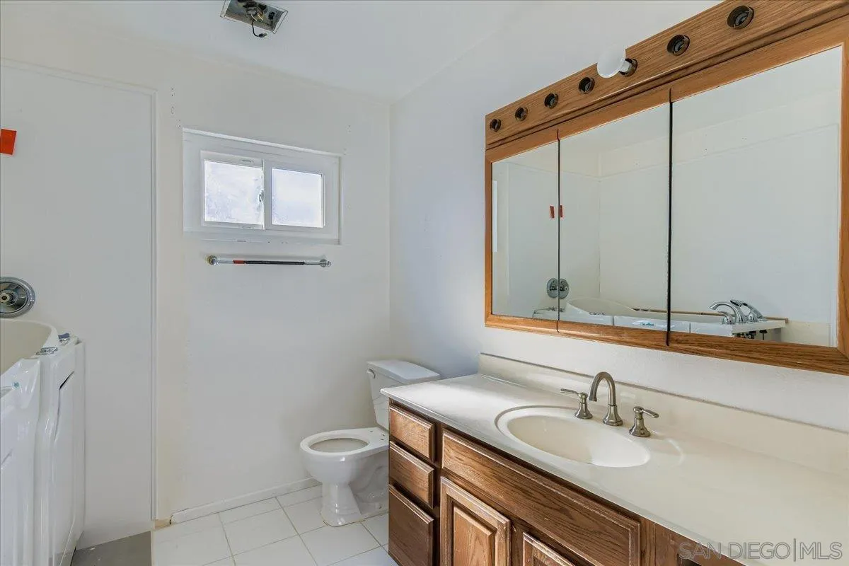 3245 Valley Street Carlsbad, CA 92008 - Photo 24 of 30 a bathroom with a granite countertop sink a toilet and a mirror