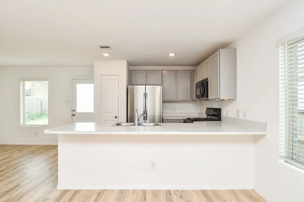 a large white kitchen with kitchen island granite countertop a sink and dishwasher a stove with wooden floors