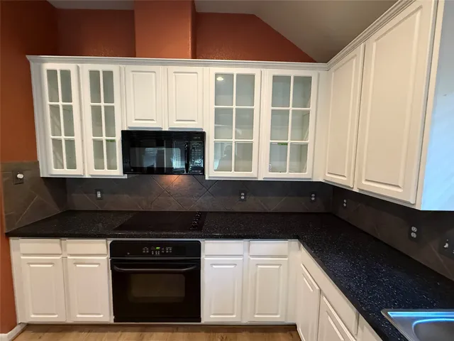 a kitchen with granite countertop white cabinets and black appliances