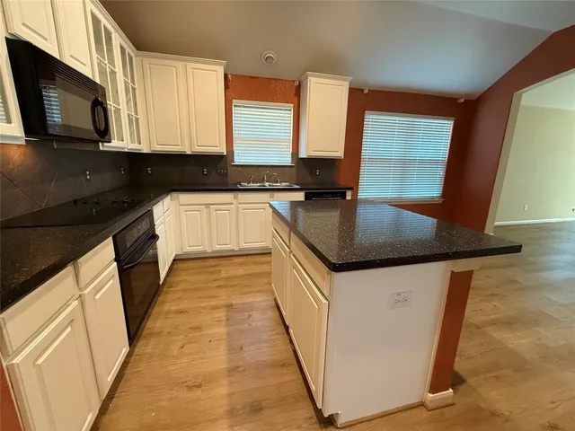 a kitchen with granite countertop a sink a stove top oven and cabinetry