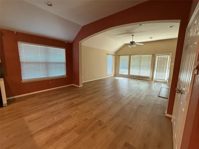 an empty room with wooden floor and windows