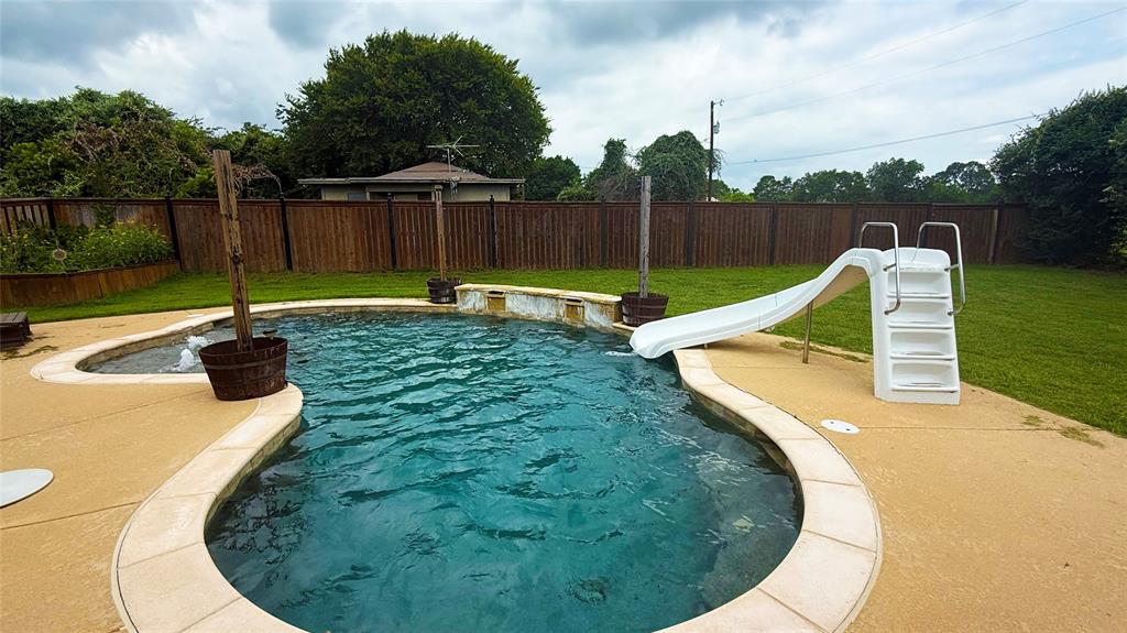 1356 Kerry Lane Azle, TX 76020 - Photo 21 of 27 Curved in-ground swimming pool with an integrated spa, concrete decking, and a white pool slide