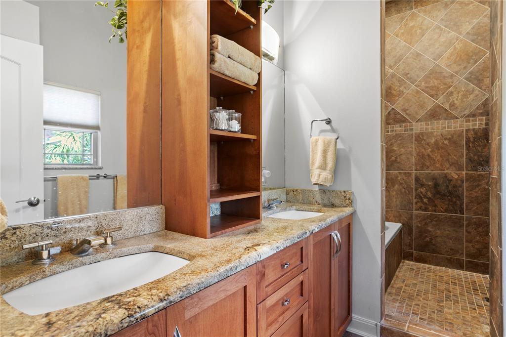 2421 Brevard Road Northeast St. Petersburg, FL 33704 - Photo 24 of 35 a bathroom with a granite countertop sink a mirror and shower