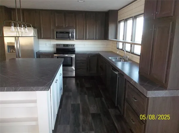a kitchen with stainless steel appliances granite countertop a refrigerator a sink a stove and wooden cabinets