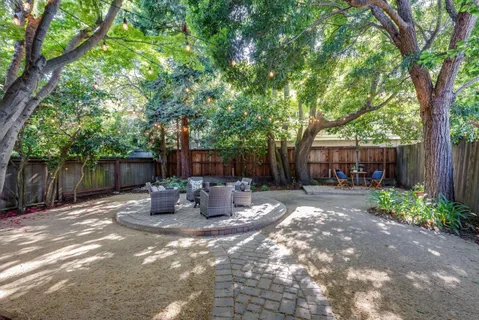 a view of a patio with table and chairs potted plants and large tree