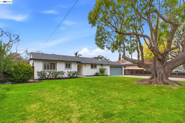 a view of a house with a big yard and large trees