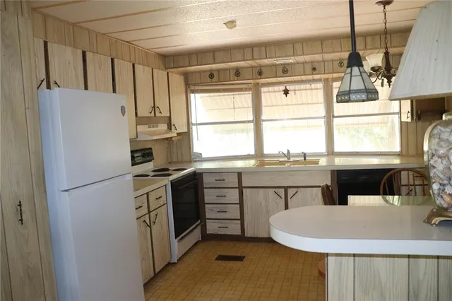 a kitchen with stainless steel appliances a refrigerator a sink a stove a dining table and chairs